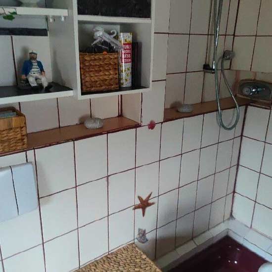 Alte Dusche mit kleinen weißen Fliesen und dunkel verfärbten Fugen
